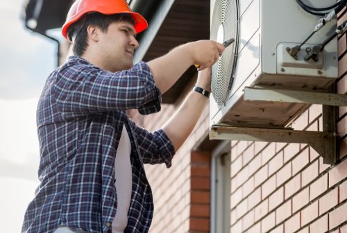 Male technician repairing outdoor air conditioning system